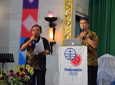 A Chinese man speaks behind a podium with an Indonesian man providing interpretation
