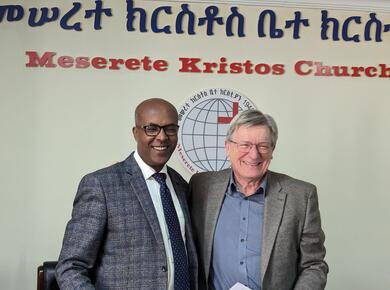 smiling men stand side by side; an African man and a white man
