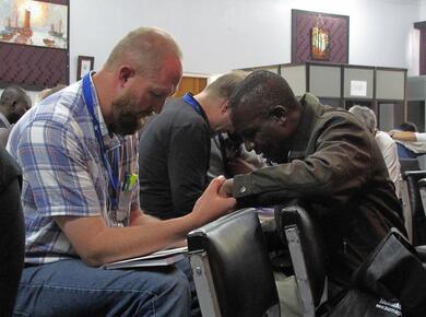 a black man and a white man hold hands in prayer