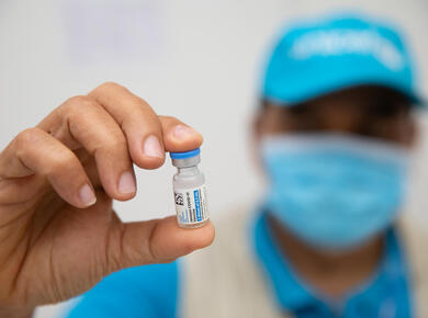 a UN-clad masked worker holds up a vial