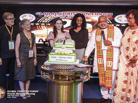 a white couple, two young women, an african couple display an anniversary cake
